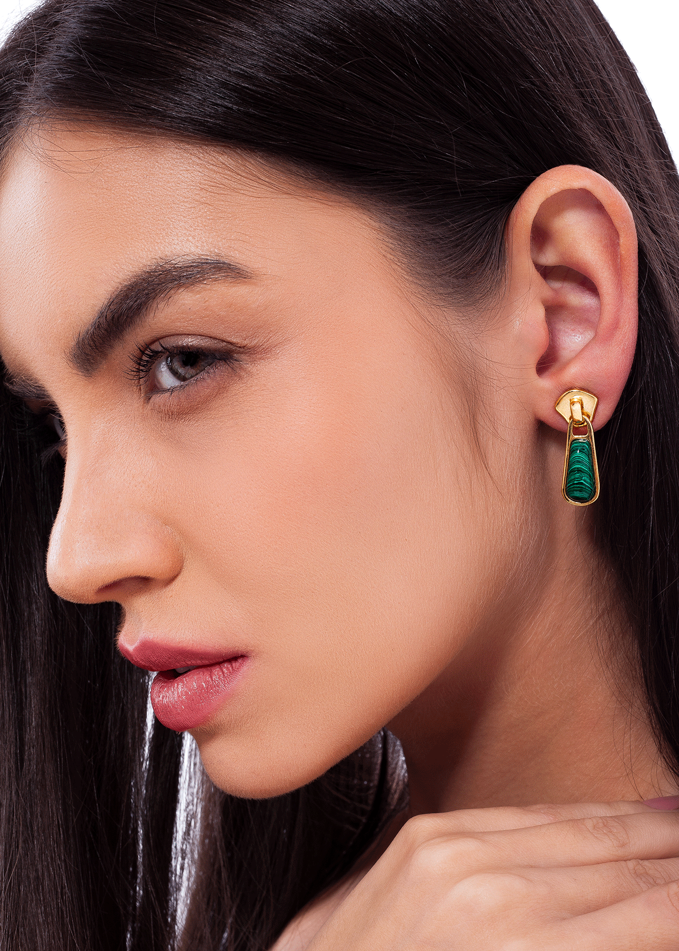 Close-up of a woman wearing a gold and green earring.