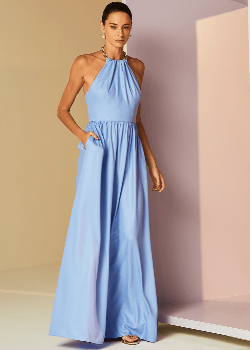 Woman wearing a long light blue dress against a neutral background