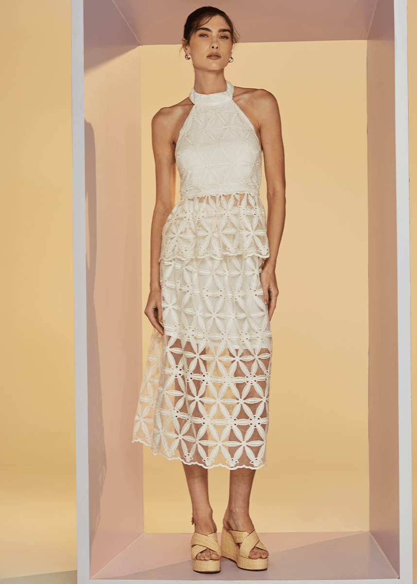 Woman wearing a white lace dress against a beige background