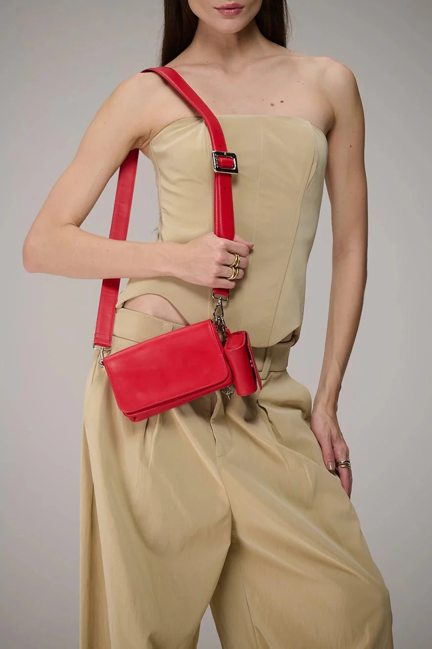 Woman holding a red handbag against a neutral background
