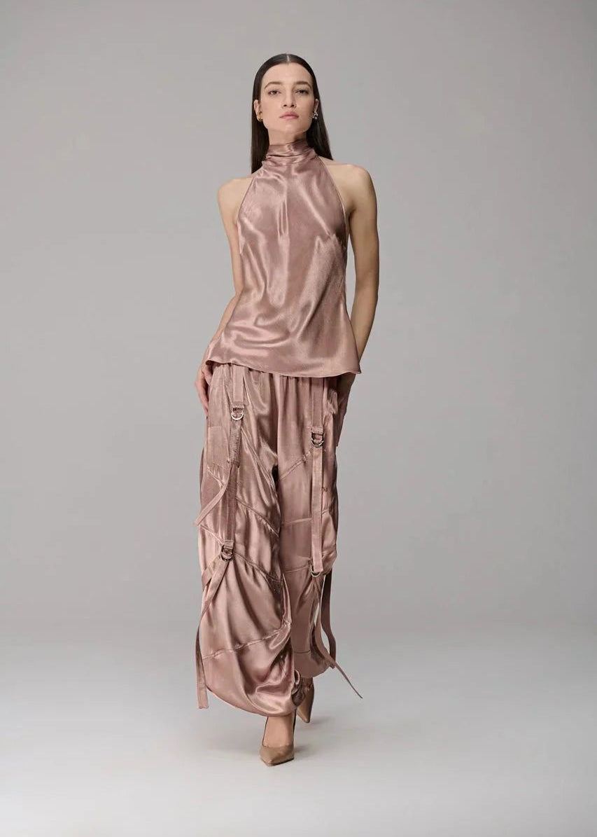 Model wearing a pink satin outfit on a gray background