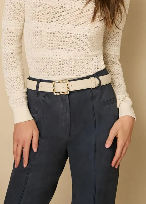 Woman wearing a cream sweater and navy blue leather pants