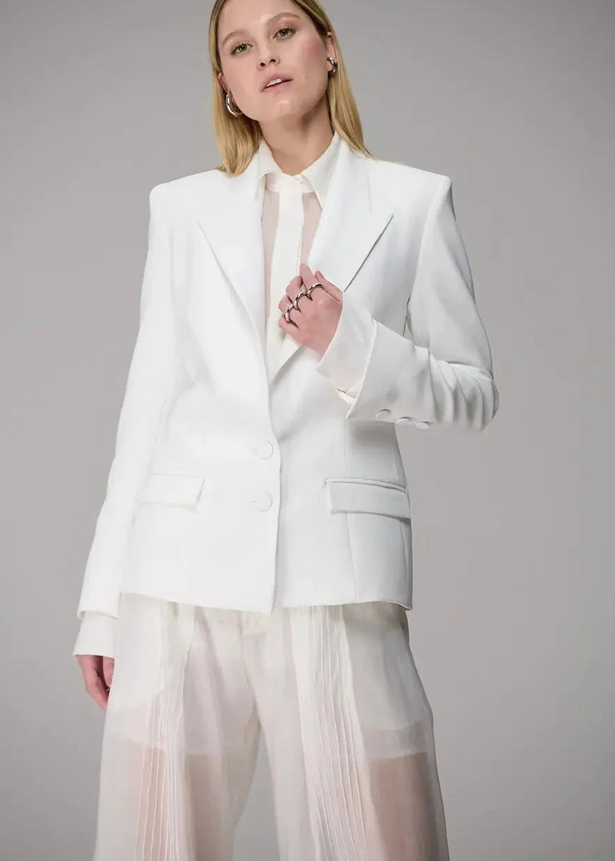 Woman wearing a white suit with sheer pants against a gray background