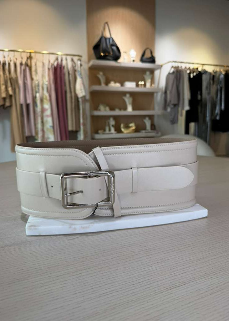 White belt with a silver buckle on a stand in a clothing store setting