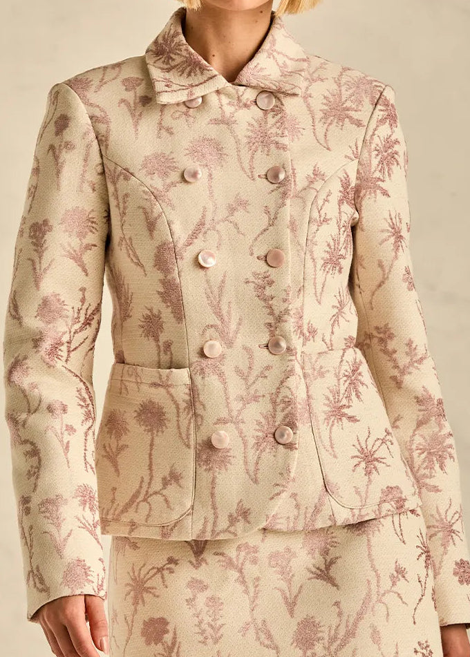 Woman wearing a floral patterned suit against a neutral background