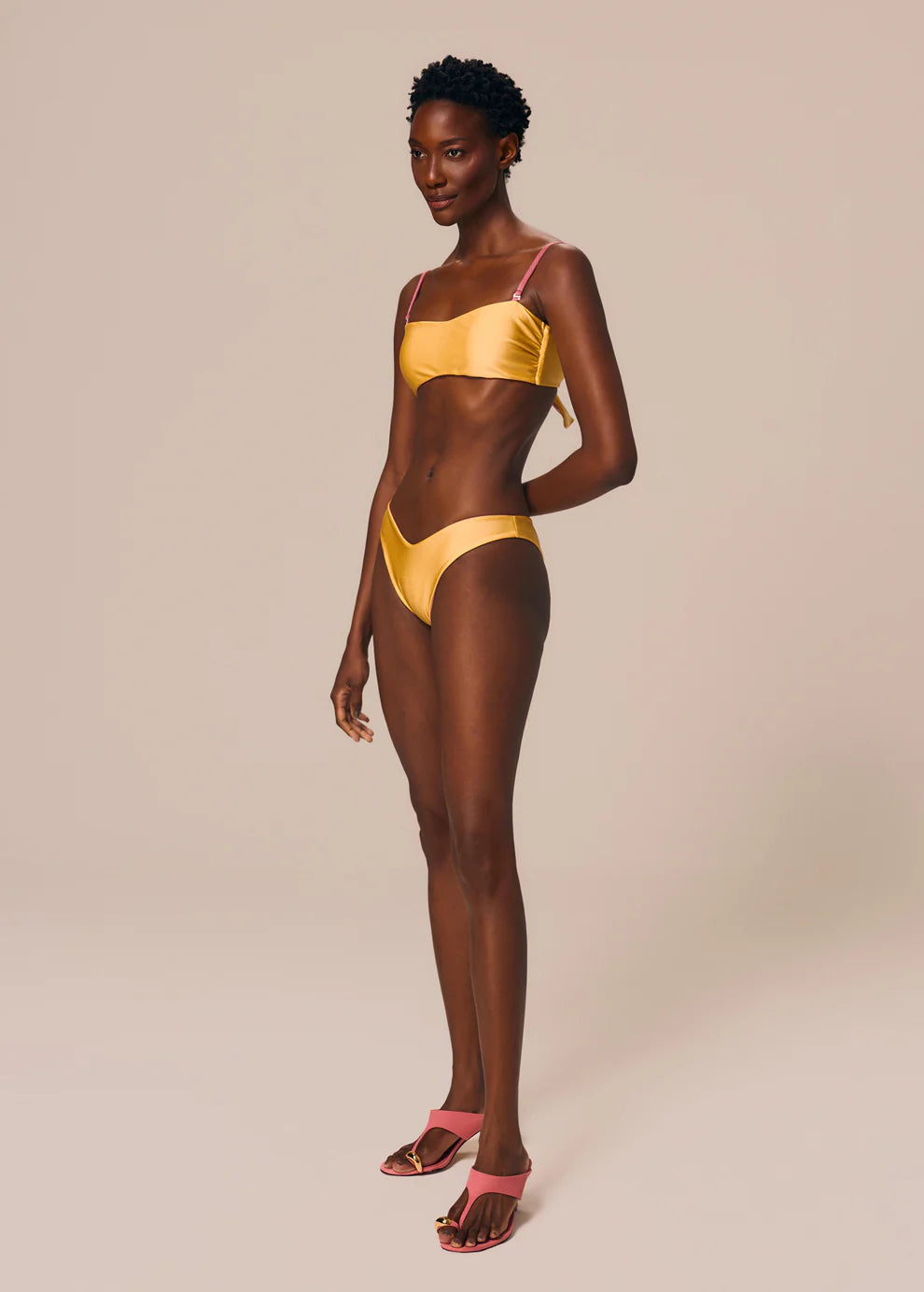 Woman wearing a yellow bikini against a beige background