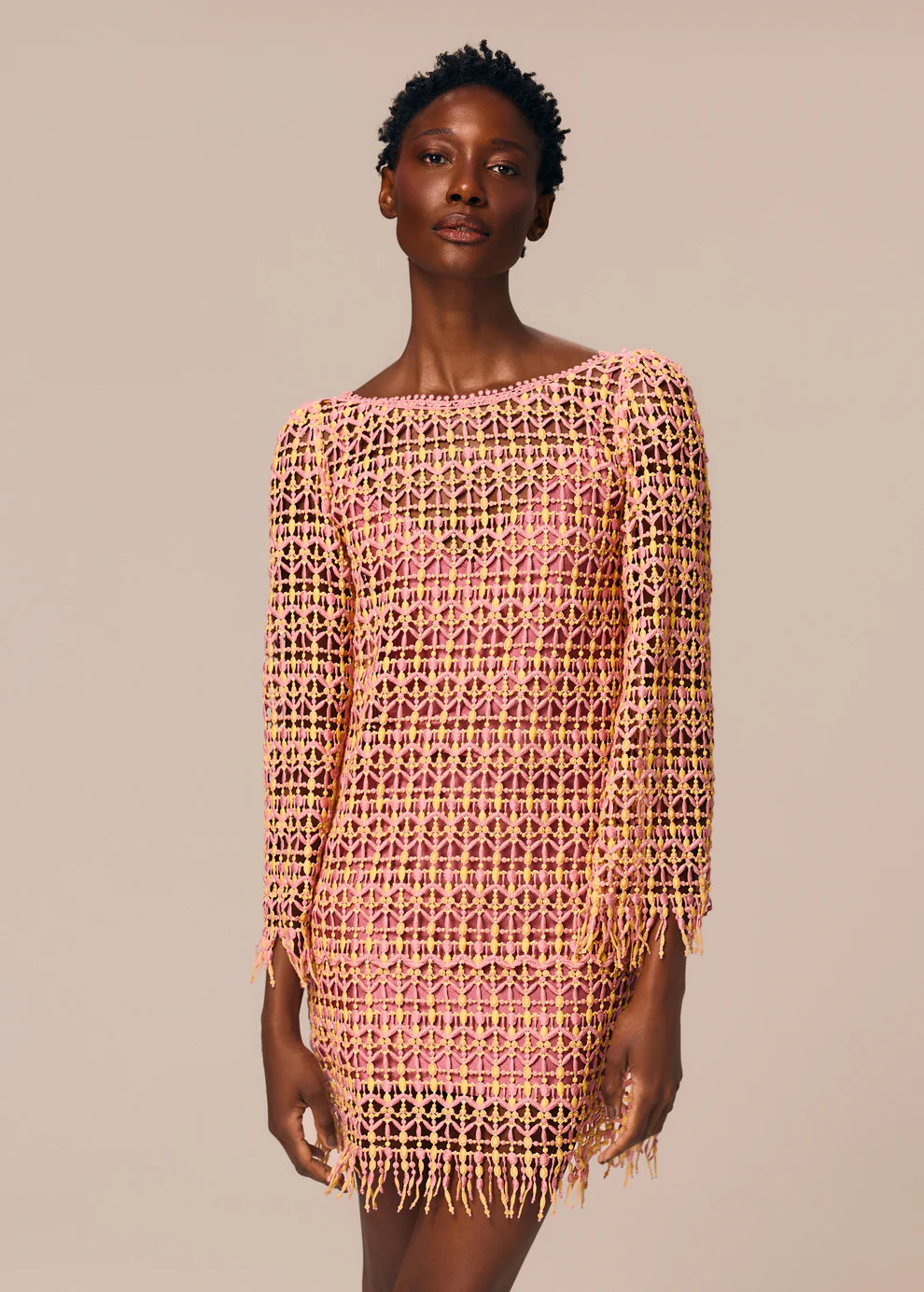 Woman wearing a pink and yellow patterned dress against a beige background