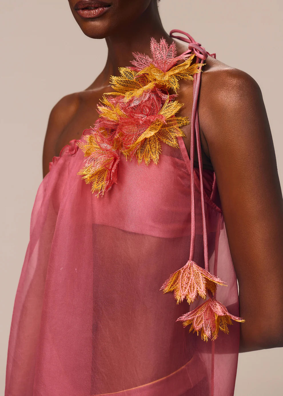 Pink floral dress with yellow accents on a neutral background