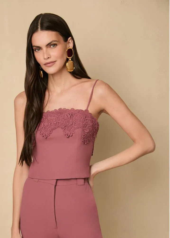 Woman wearing a pink tank with lace detailing on a beige background