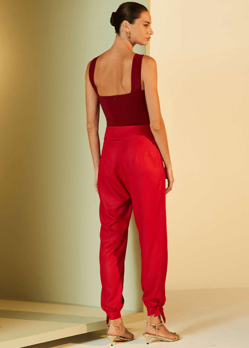 Woman wearing a red jumpsuit against a beige wall