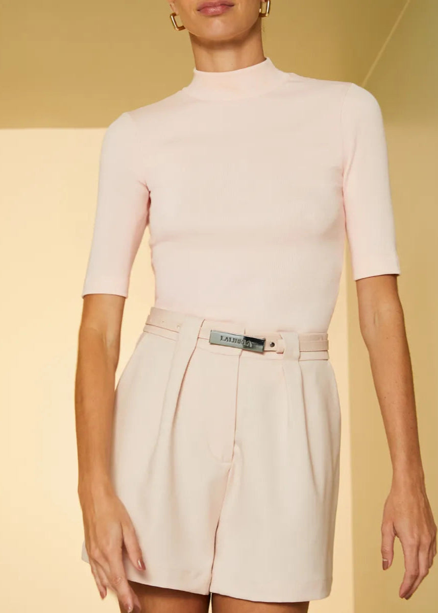 Person wearing a light pink top and beige skirt on a yellow background
