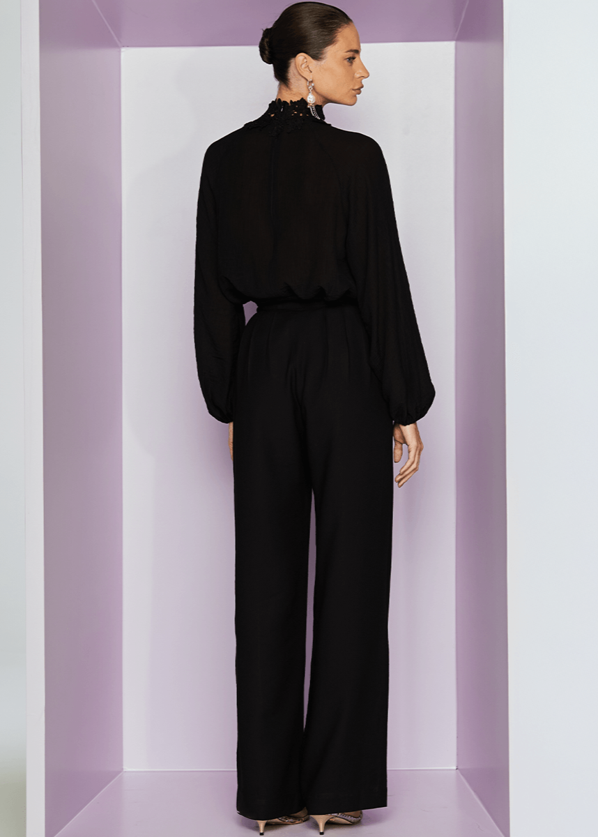 Woman wearing a black outfit standing in a minimalistic setting with a purple border.