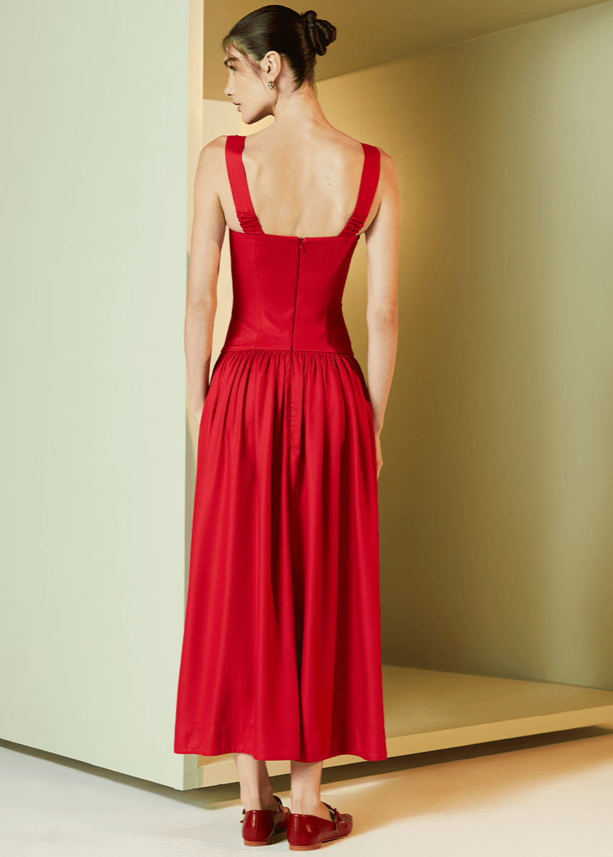 Woman wearing a red dress standing in a minimalistic room with a neutral color scheme.
