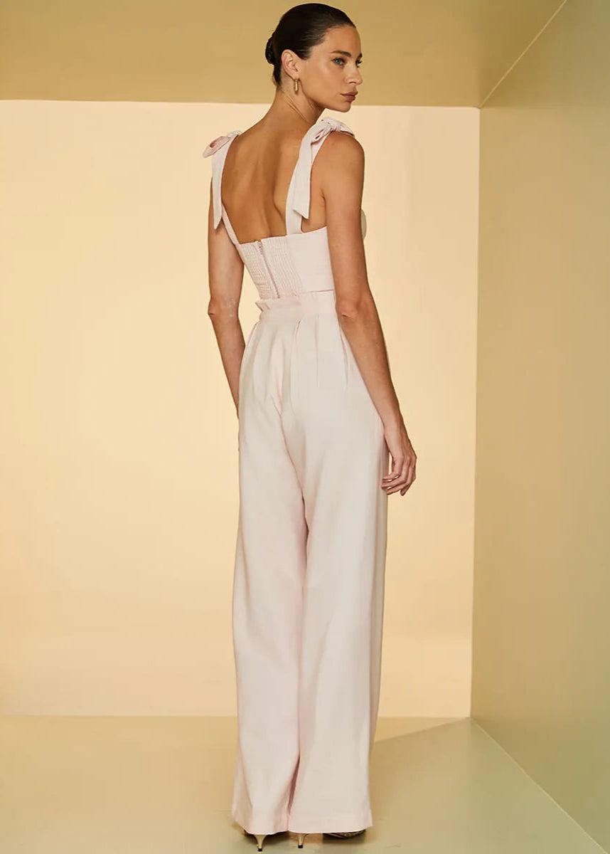 Woman wearing a white dress with thin straps in a softly lit room.