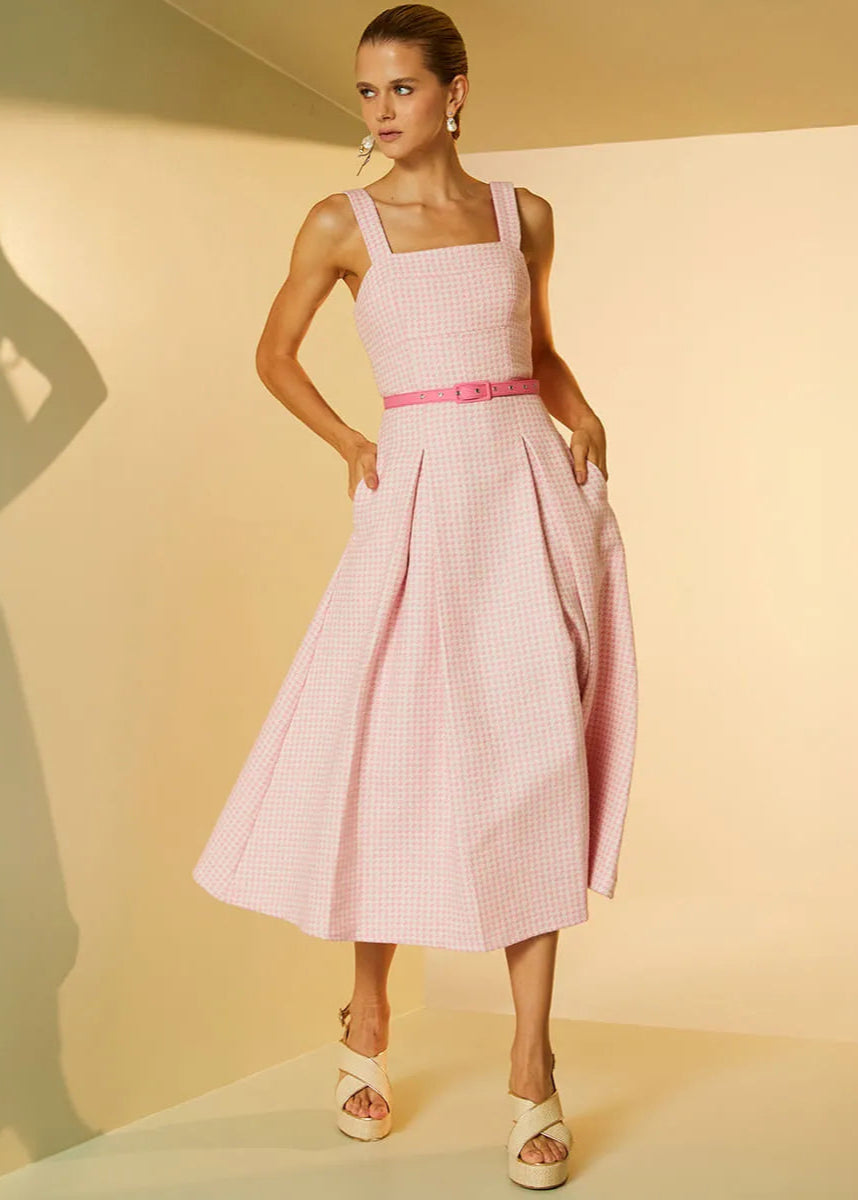 Woman wearing a pink checkered dress with a belt against a beige background