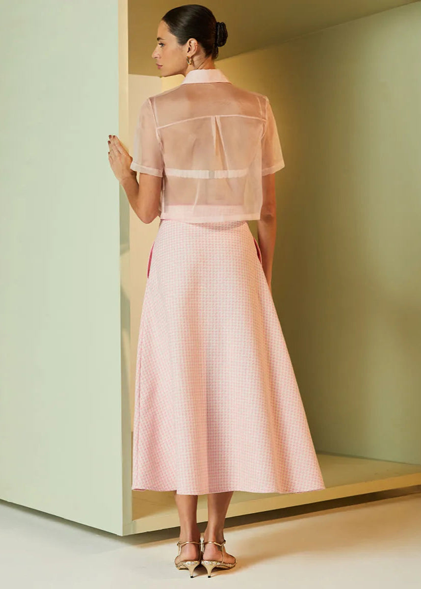Woman wearing a light pink dress with sheer sleeves in a minimalistic setting