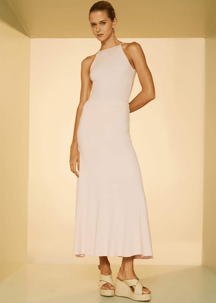 Woman wearing a white dress standing against a plain background