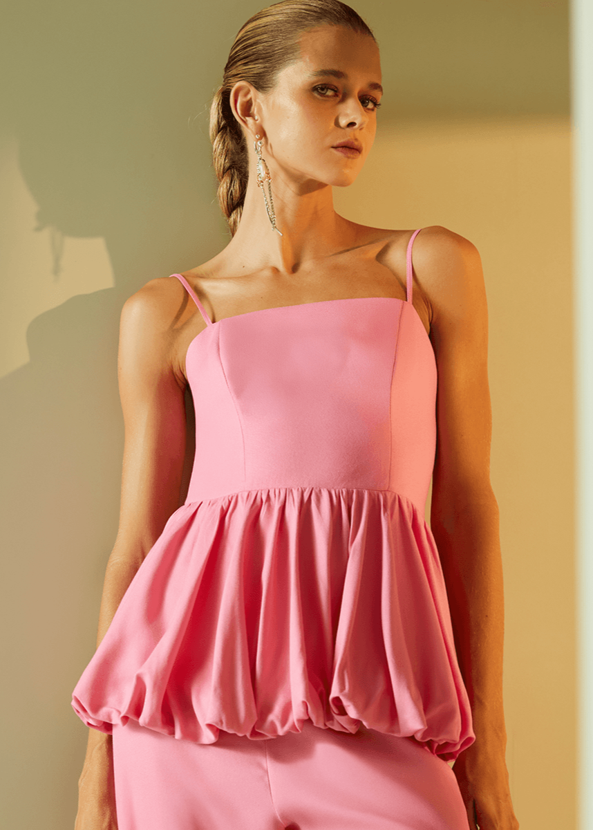 Woman wearing a pink dress standing against a neutral background