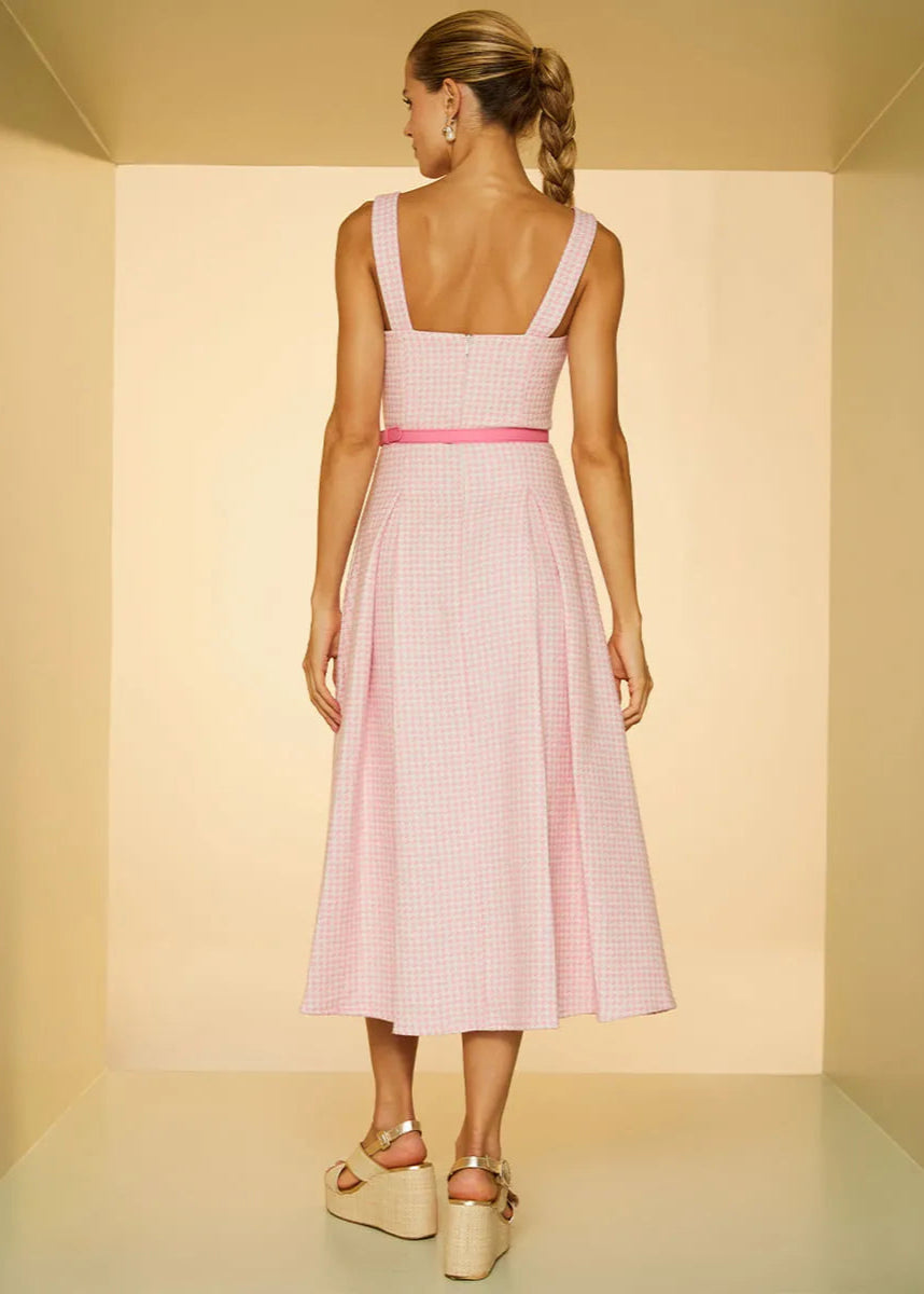 Woman wearing a pink checkered dress in a neutral setting