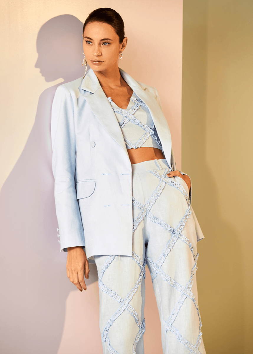 Woman wearing a light blue outfit with a jacket and skirt against a plain background