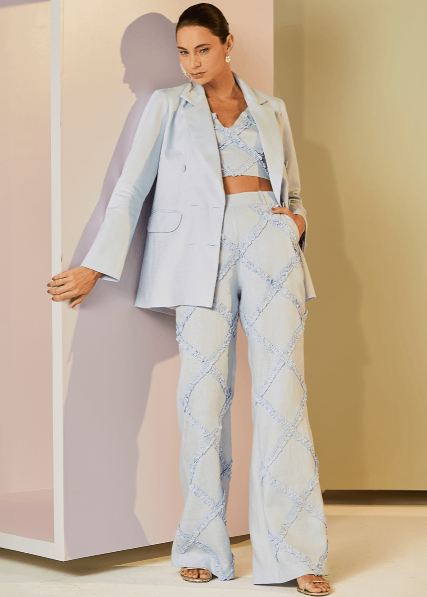 Woman in a light blue outfit standing against a neutral background