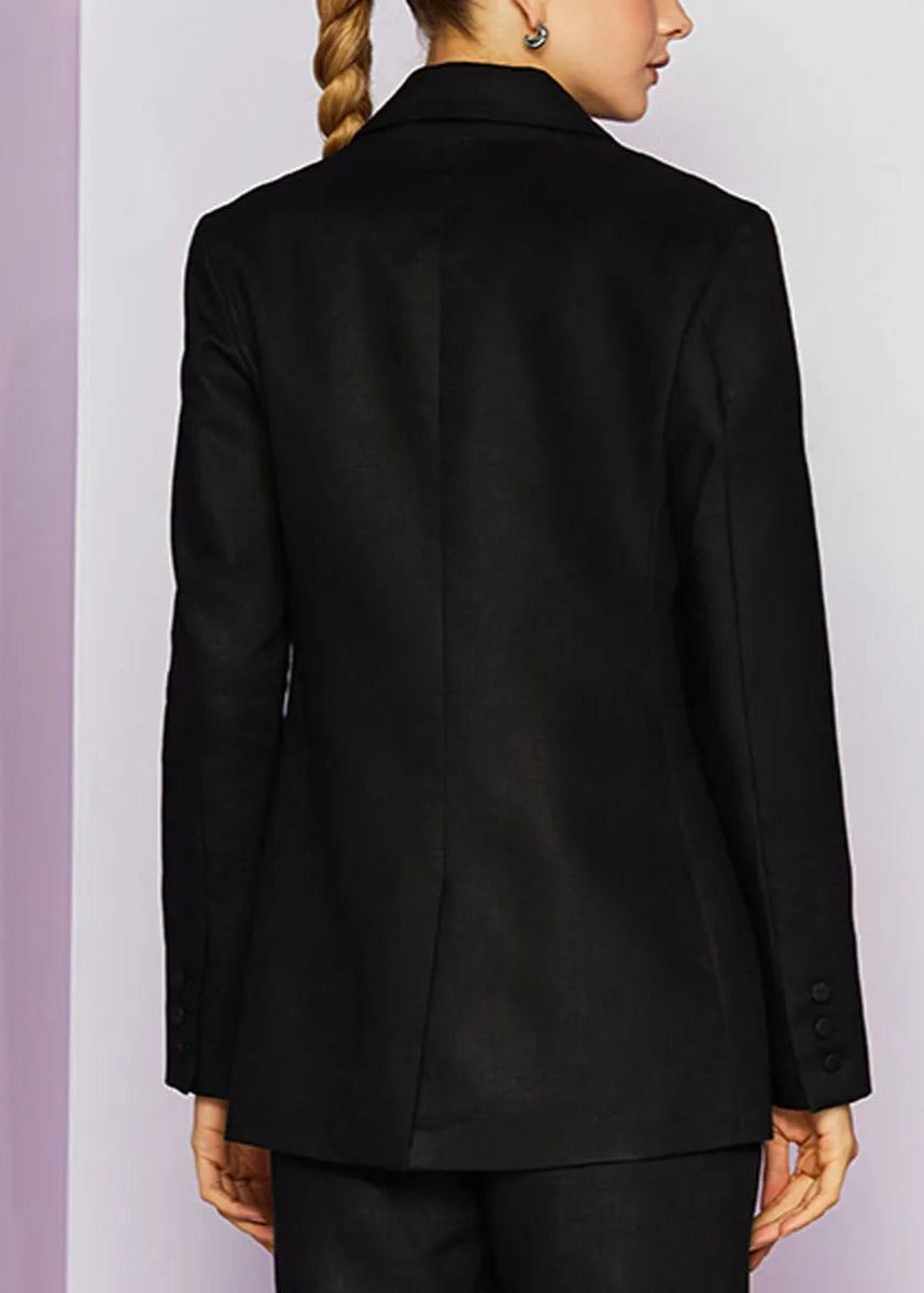 Black suit jacket worn by a person on a light purple background