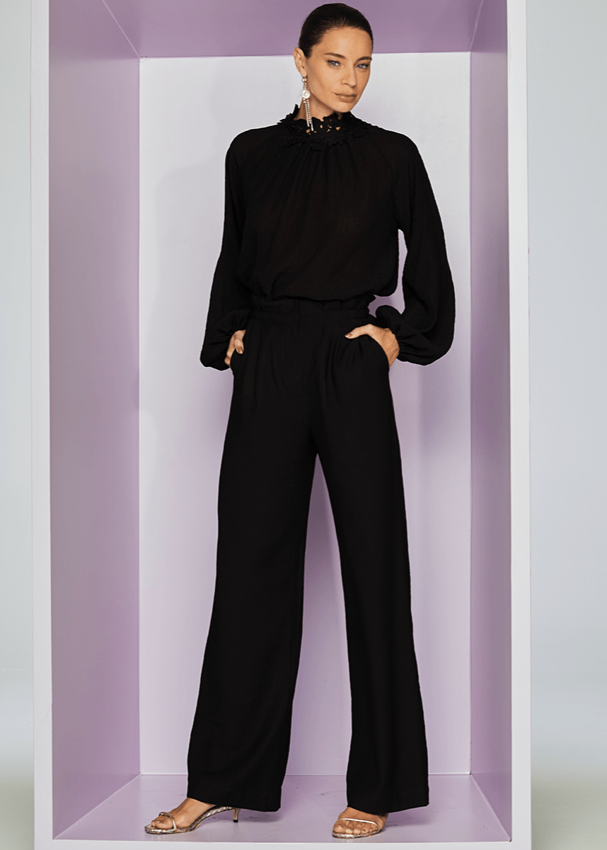 Woman wearing a black outfit standing in a white box with a purple interior.