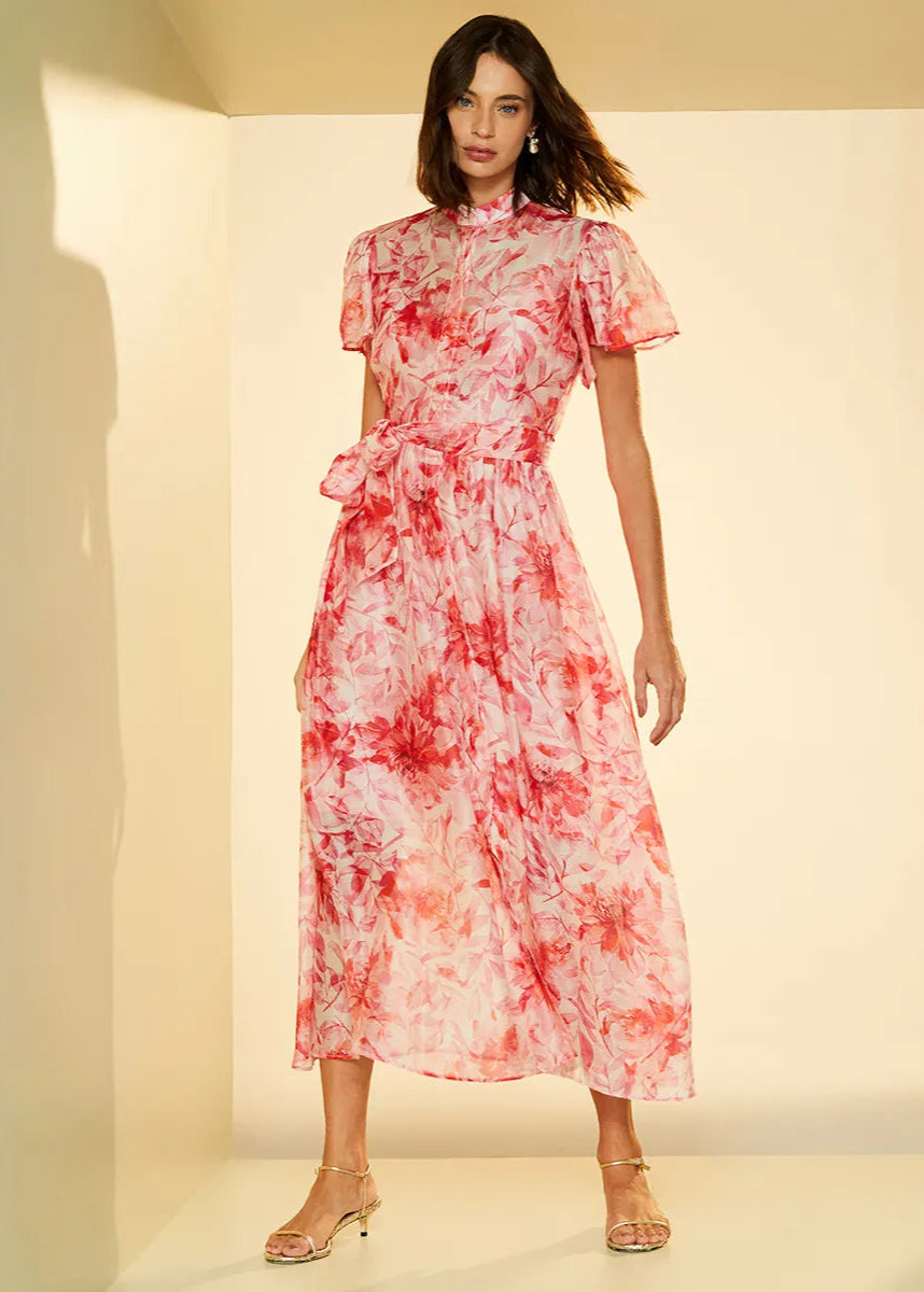 Woman wearing a red and white floral dress against a neutral background