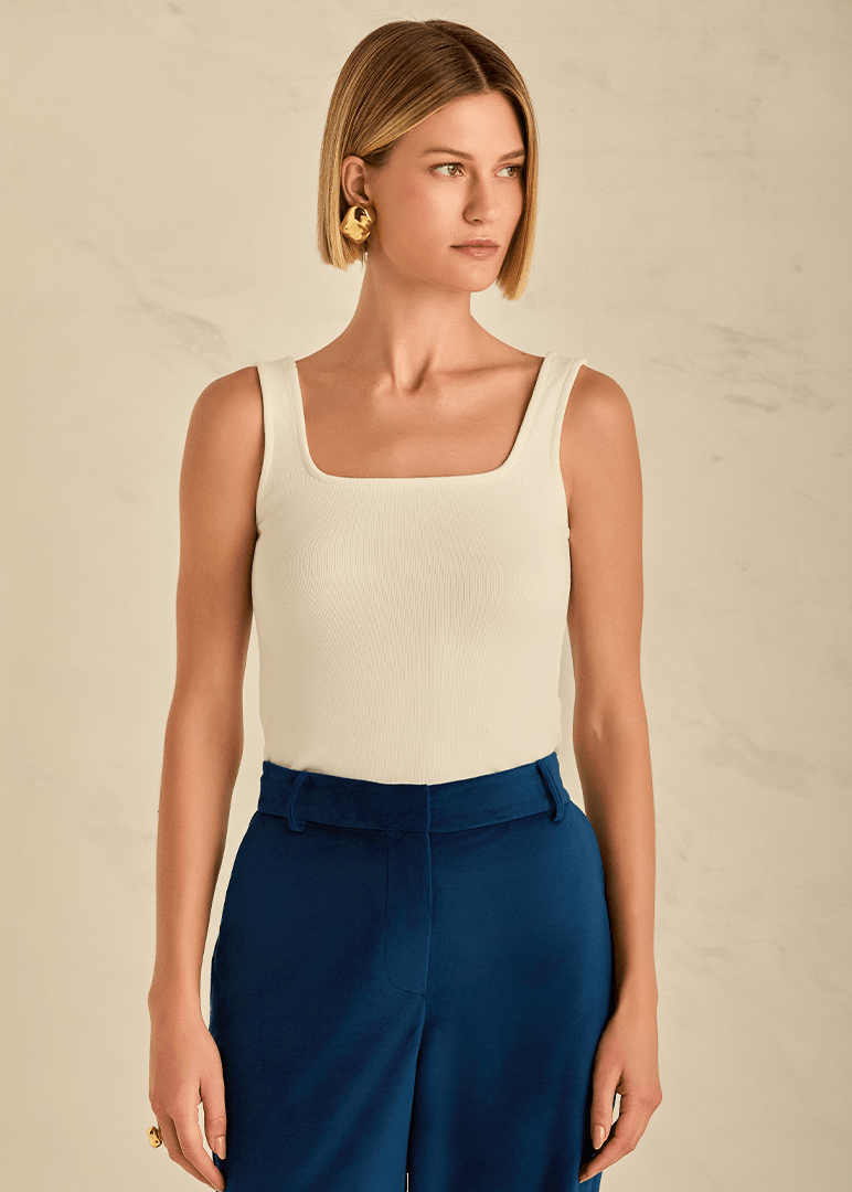 Woman wearing a beige tank top and blue pants