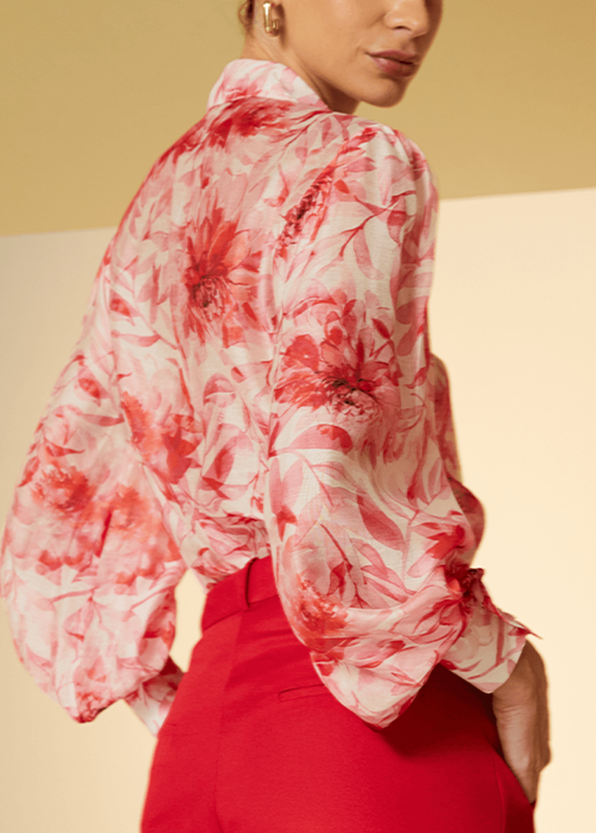 Person wearing a red and white floral blouse with a plain background