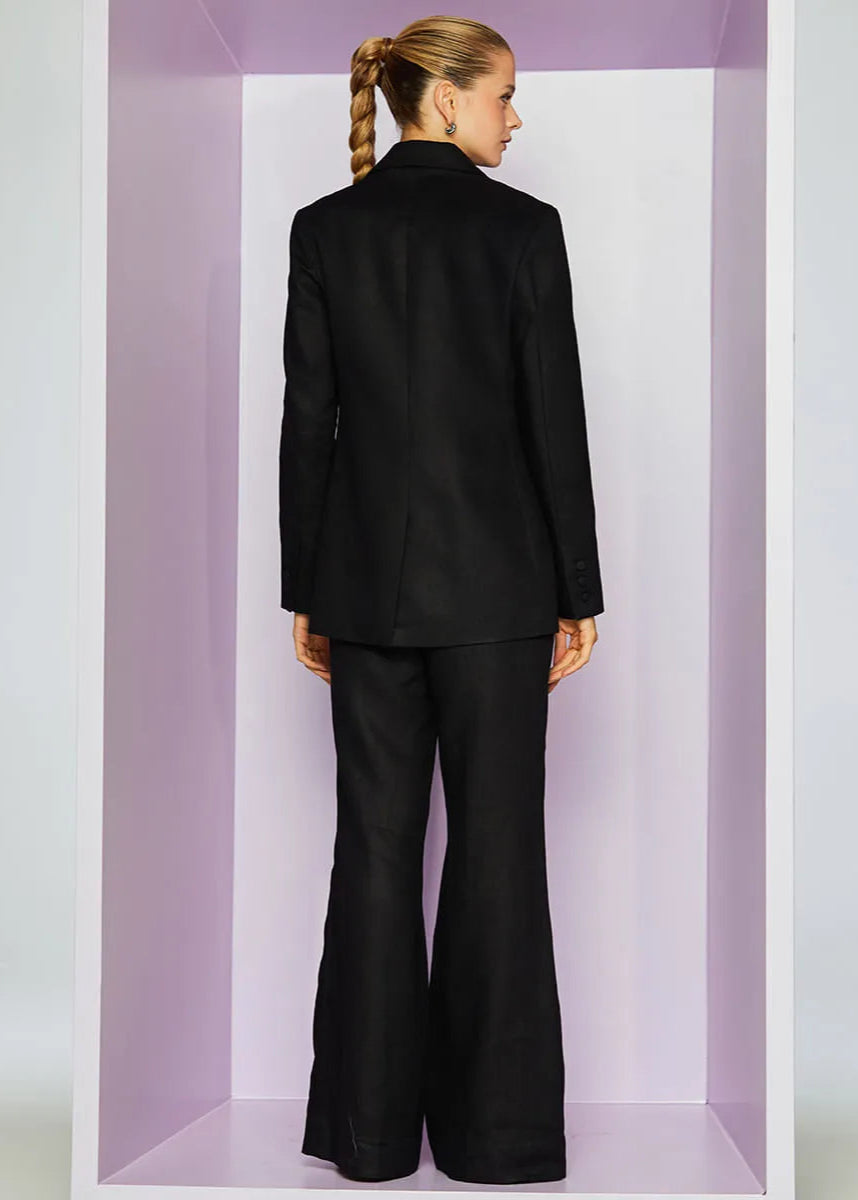 Person wearing a black suit standing inside a rectangular box with a light purple interior.
