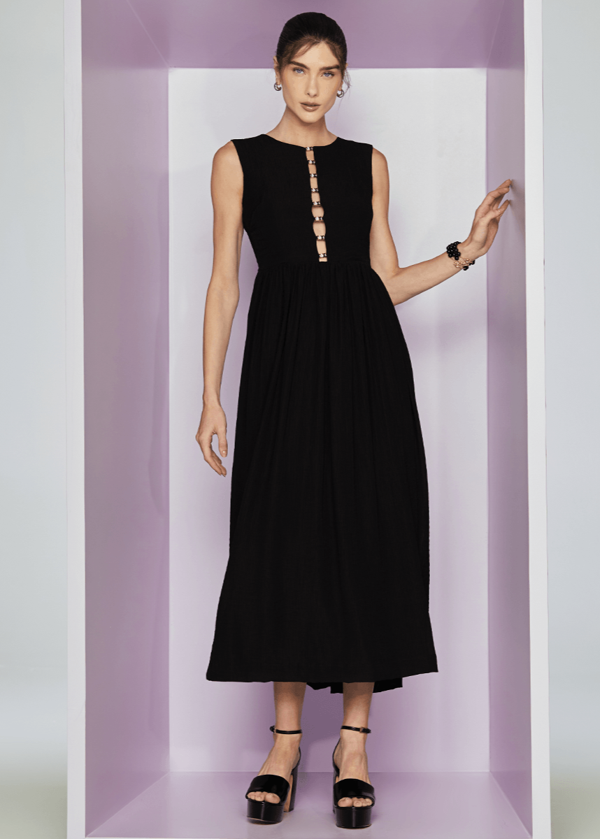Woman wearing a black dress with a button detail in a minimalistic setting
