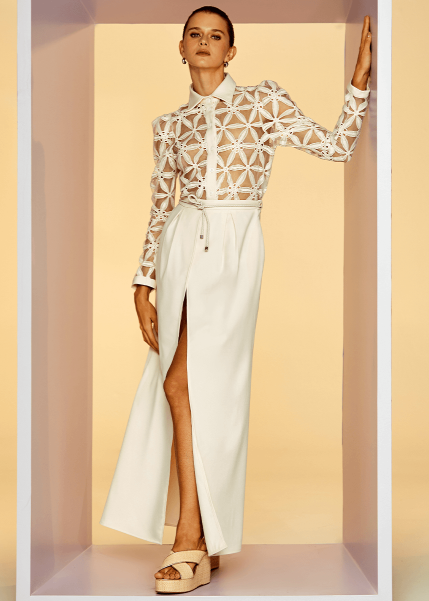 Woman wearing a white outfit with a geometric top against a beige background