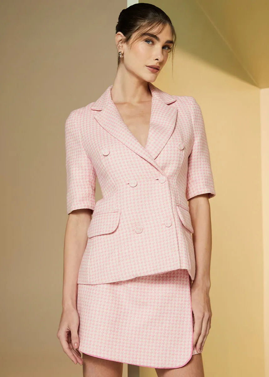 Woman wearing a pink checkered suit against a beige background