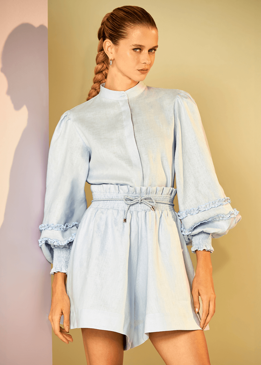 Woman wearing a light blue dress with a belt against a gradient background