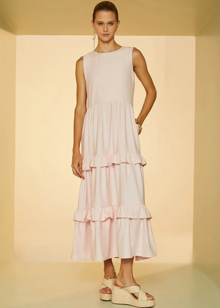 Woman wearing a light pink ruffled dress in a neutral setting