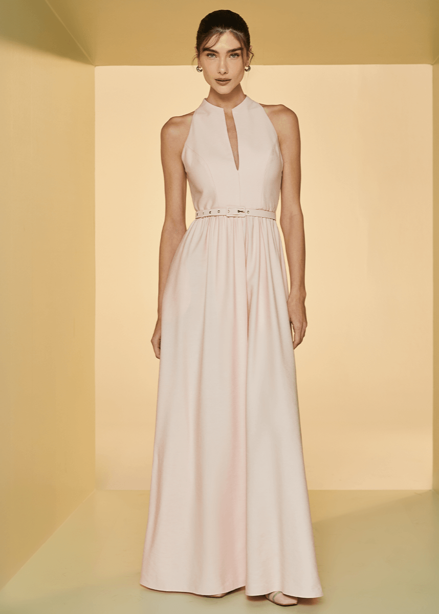 Woman wearing a long, light-colored dress against a neutral background