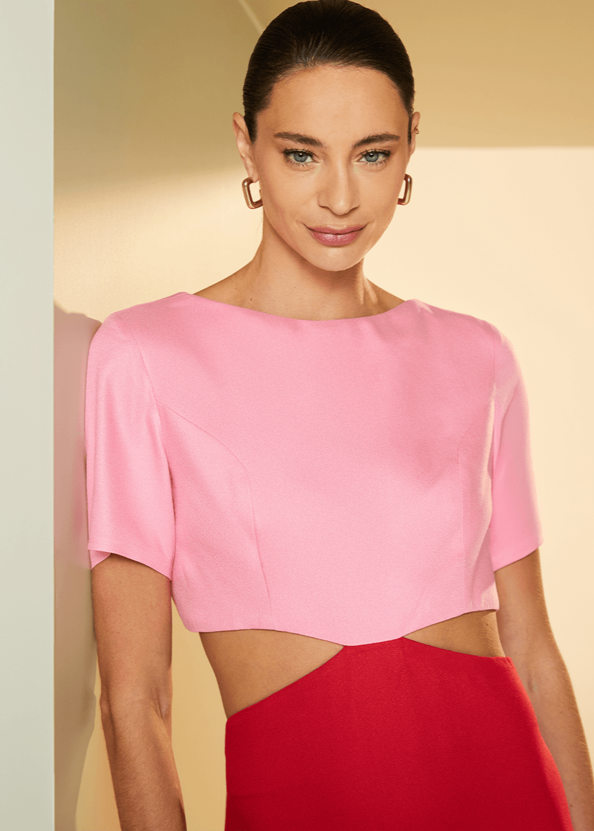 Woman wearing a pink top and red skirt against a beige background