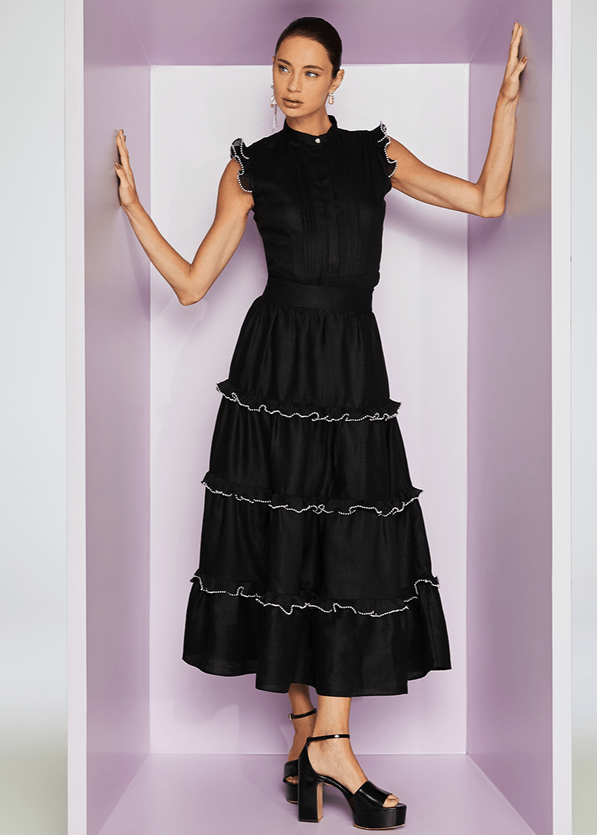 Woman wearing a black dress with ruffled layers against a white background