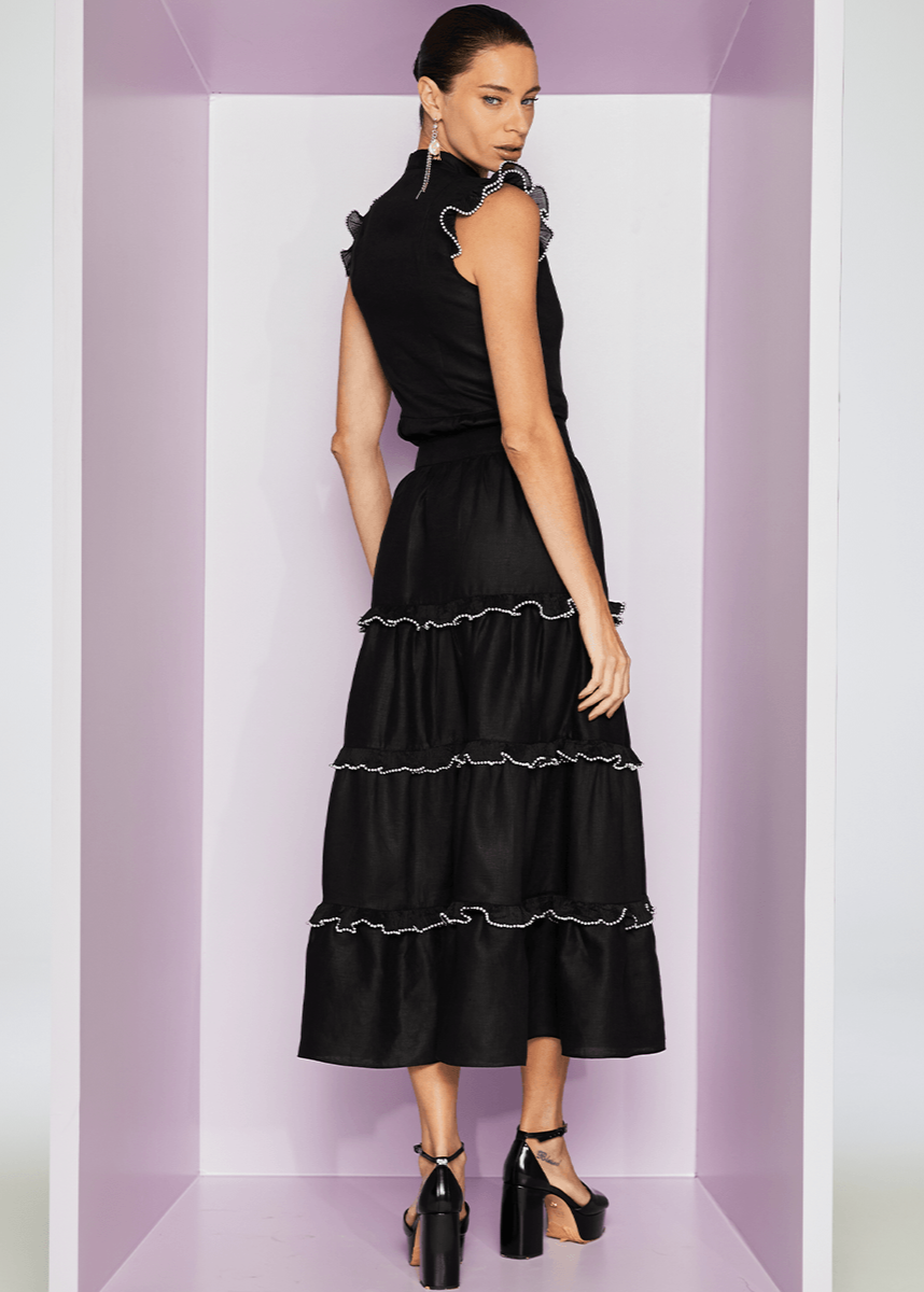 Woman wearing a black dress with ruffled details in a minimalistic setting
