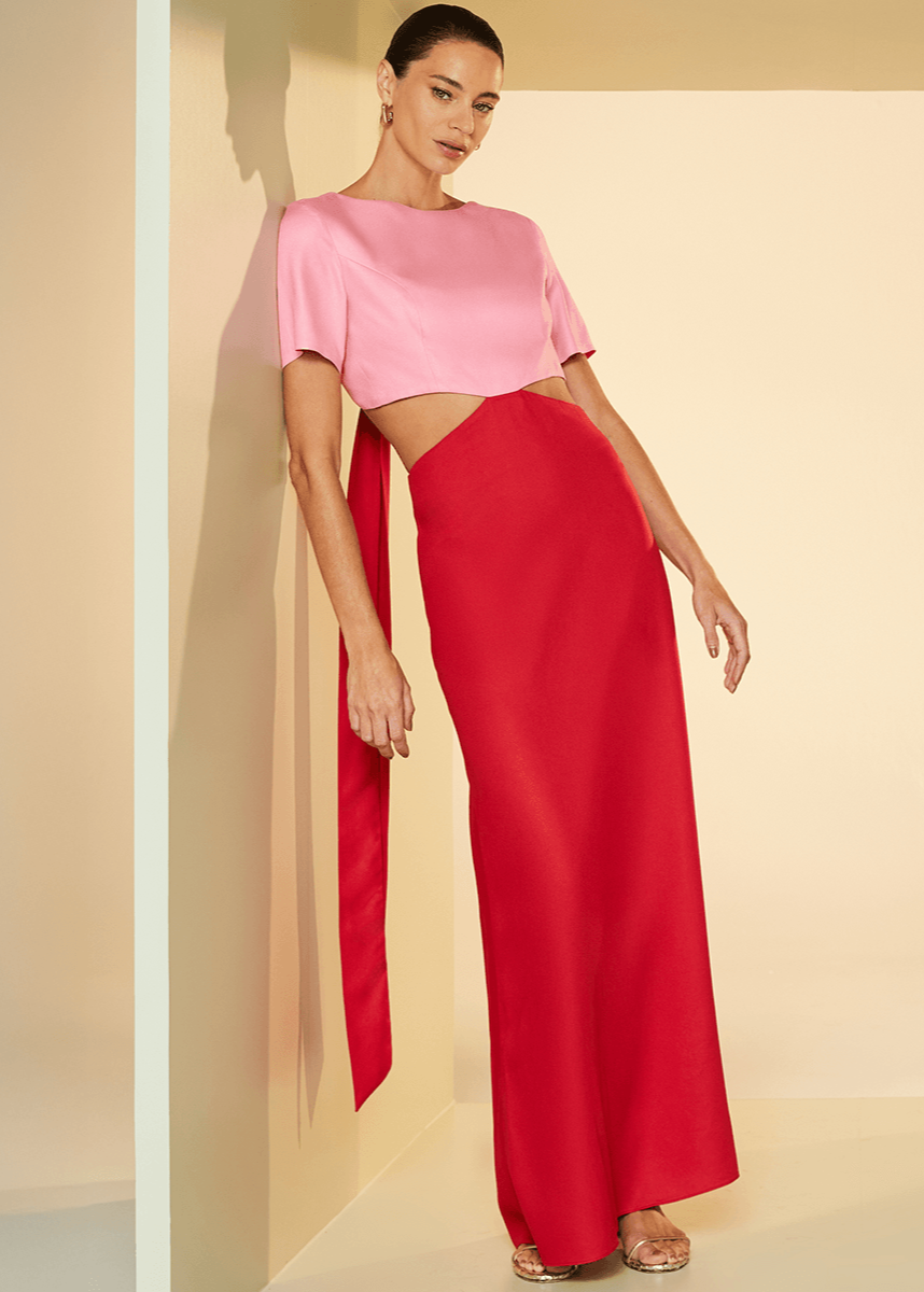 Woman wearing a pink top and red pants against a beige background