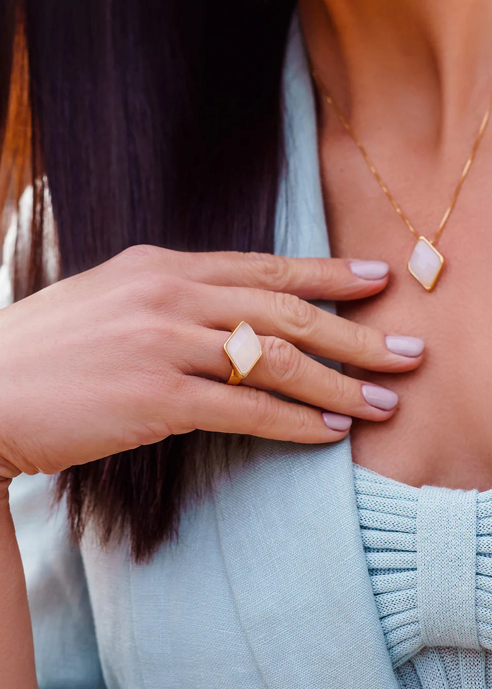 Woman wearing a gold ring and necklace with a light blue sweater