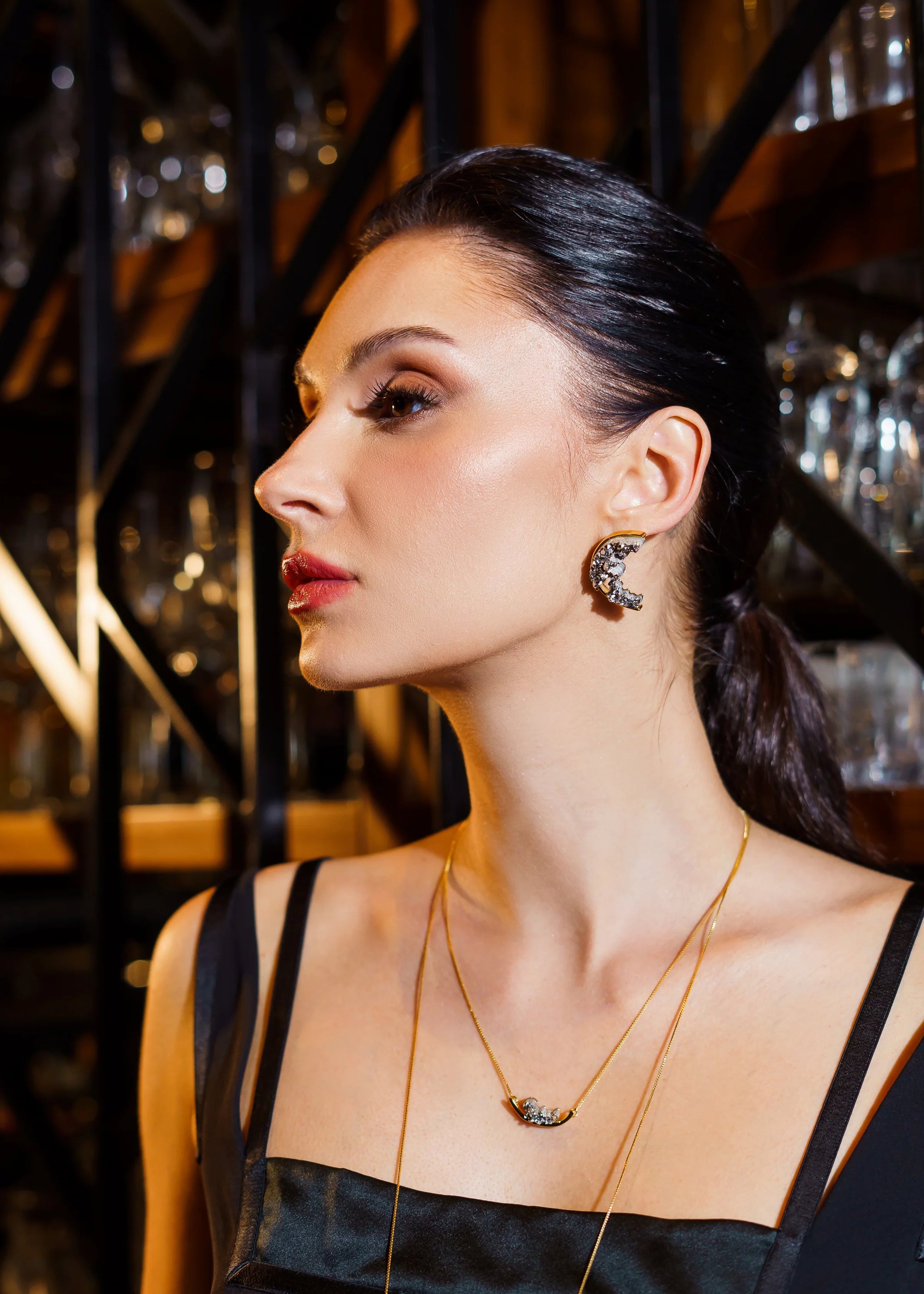 Woman wearing a necklace and earrings in a dimly lit setting