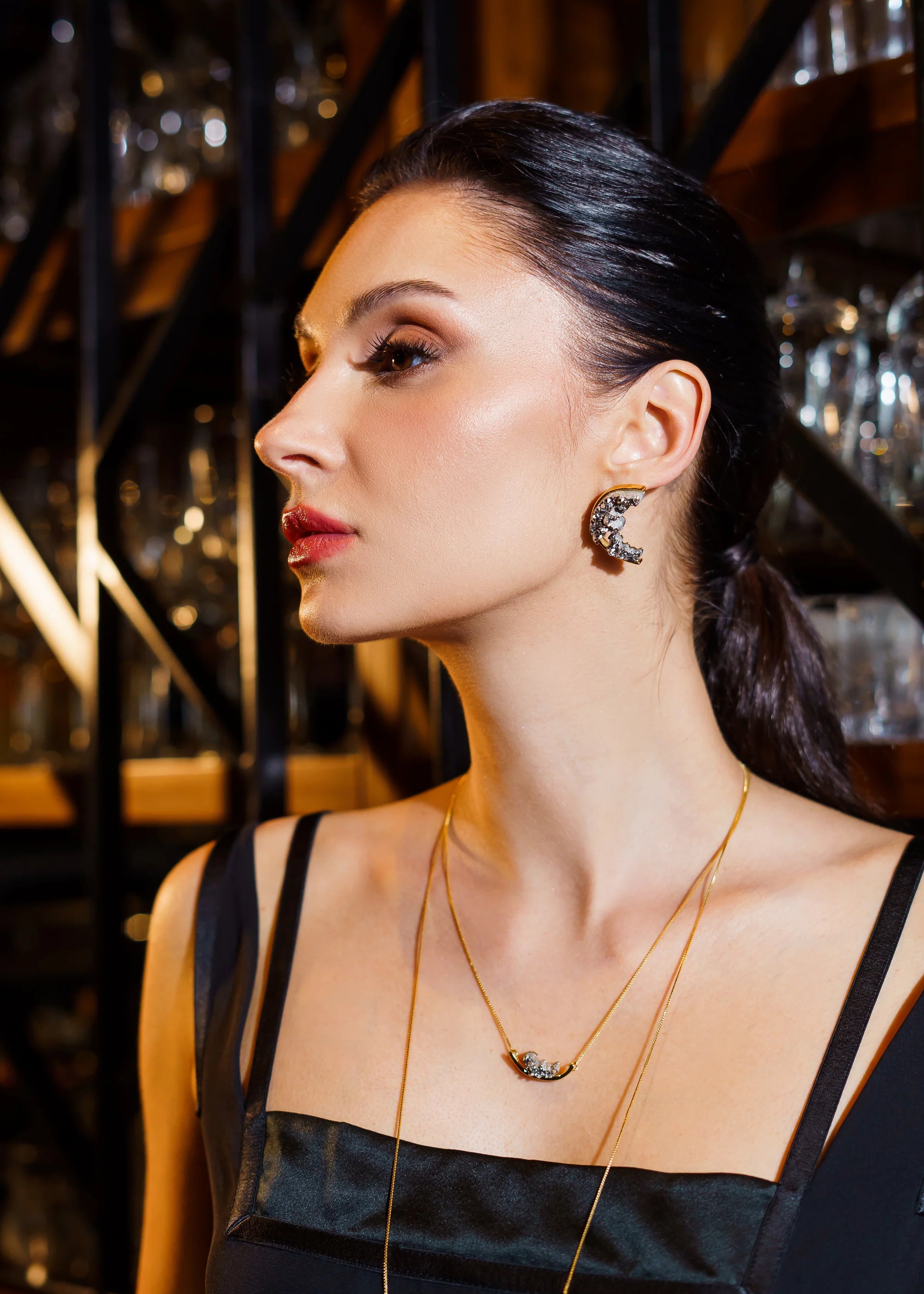 Woman wearing a necklace and earrings in a dimly lit setting