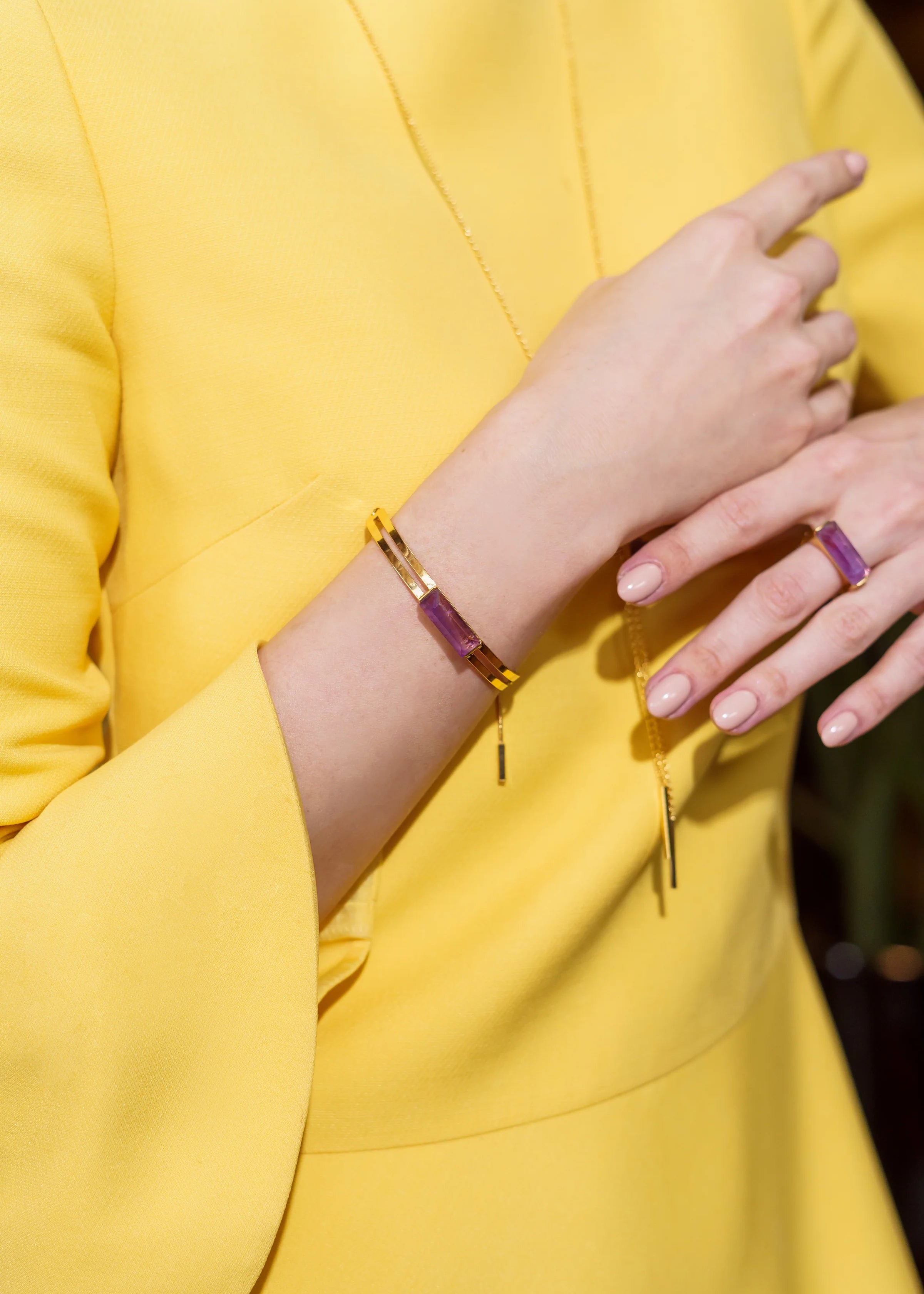 Person wearing a gold bracelet and ring with a yellow garment