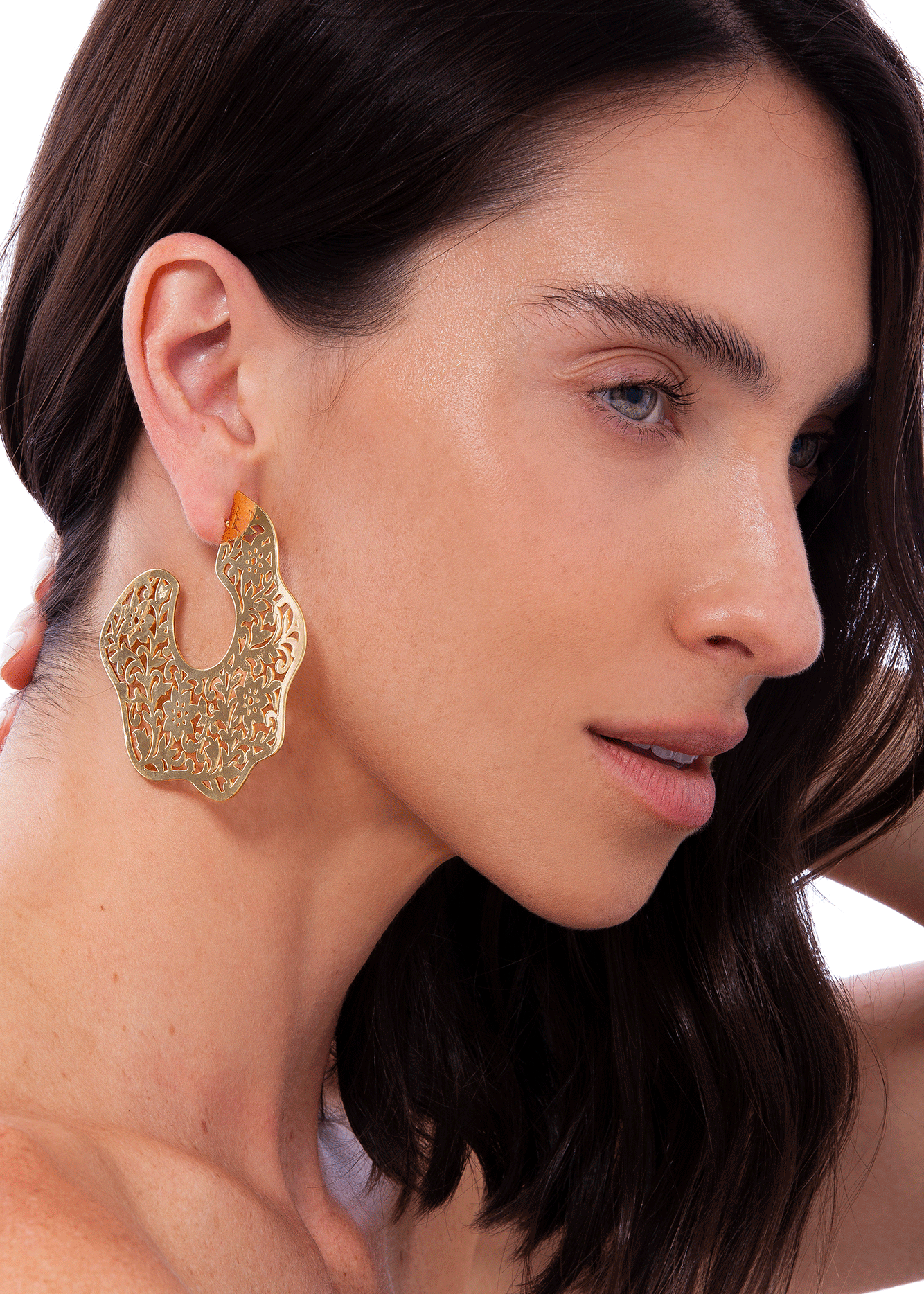Woman wearing a gold earring with a neutral background