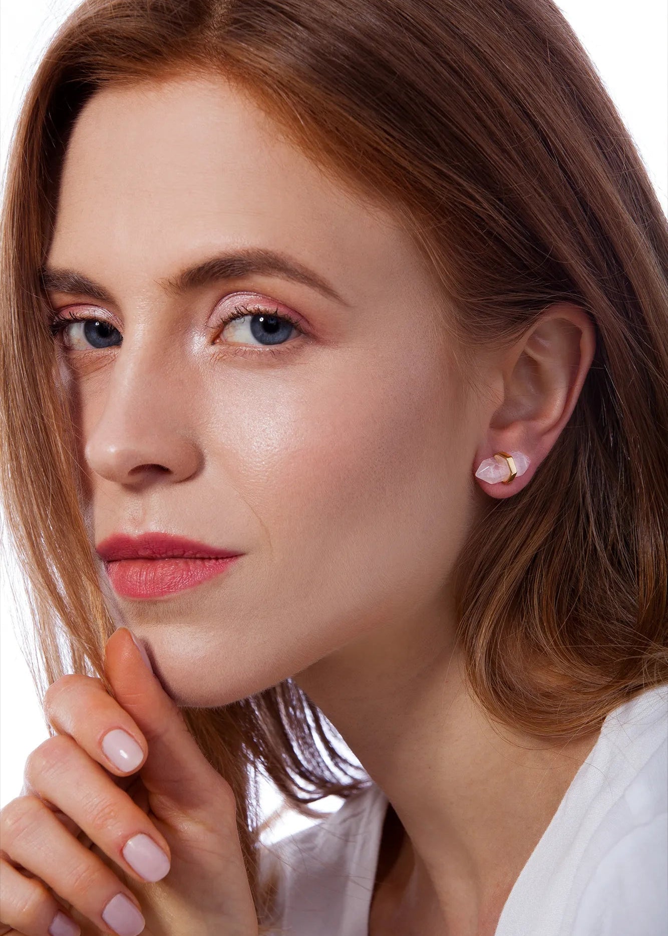 Close-up of a woman with light makeup and earrings on a white background