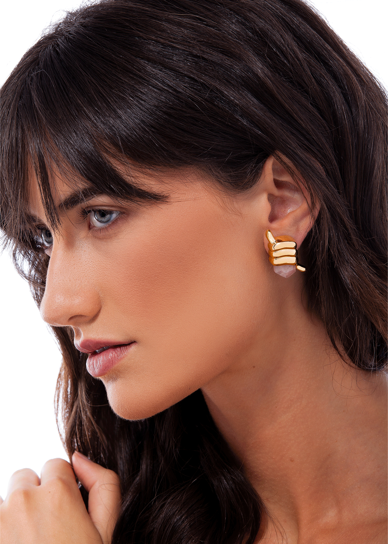 Close-up of a woman wearing gold earrings with a neutral background