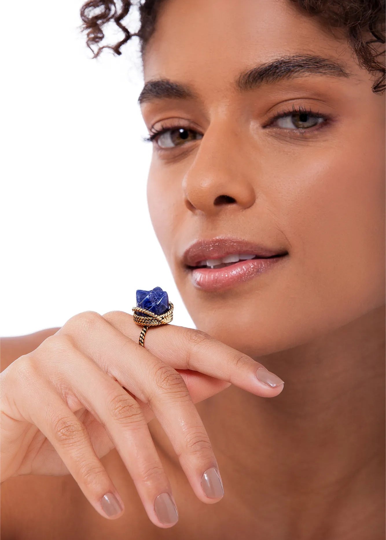 Woman wearing a ring with a blue stone on a neutral background