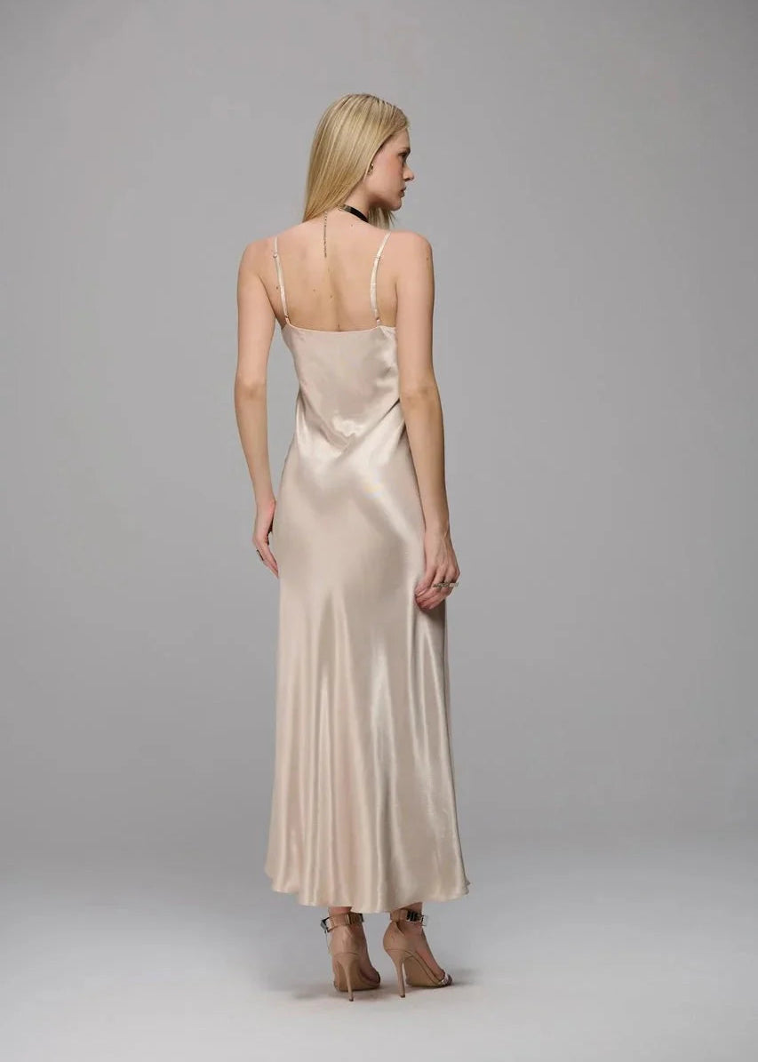 Woman wearing a beige satin dress against a gray background